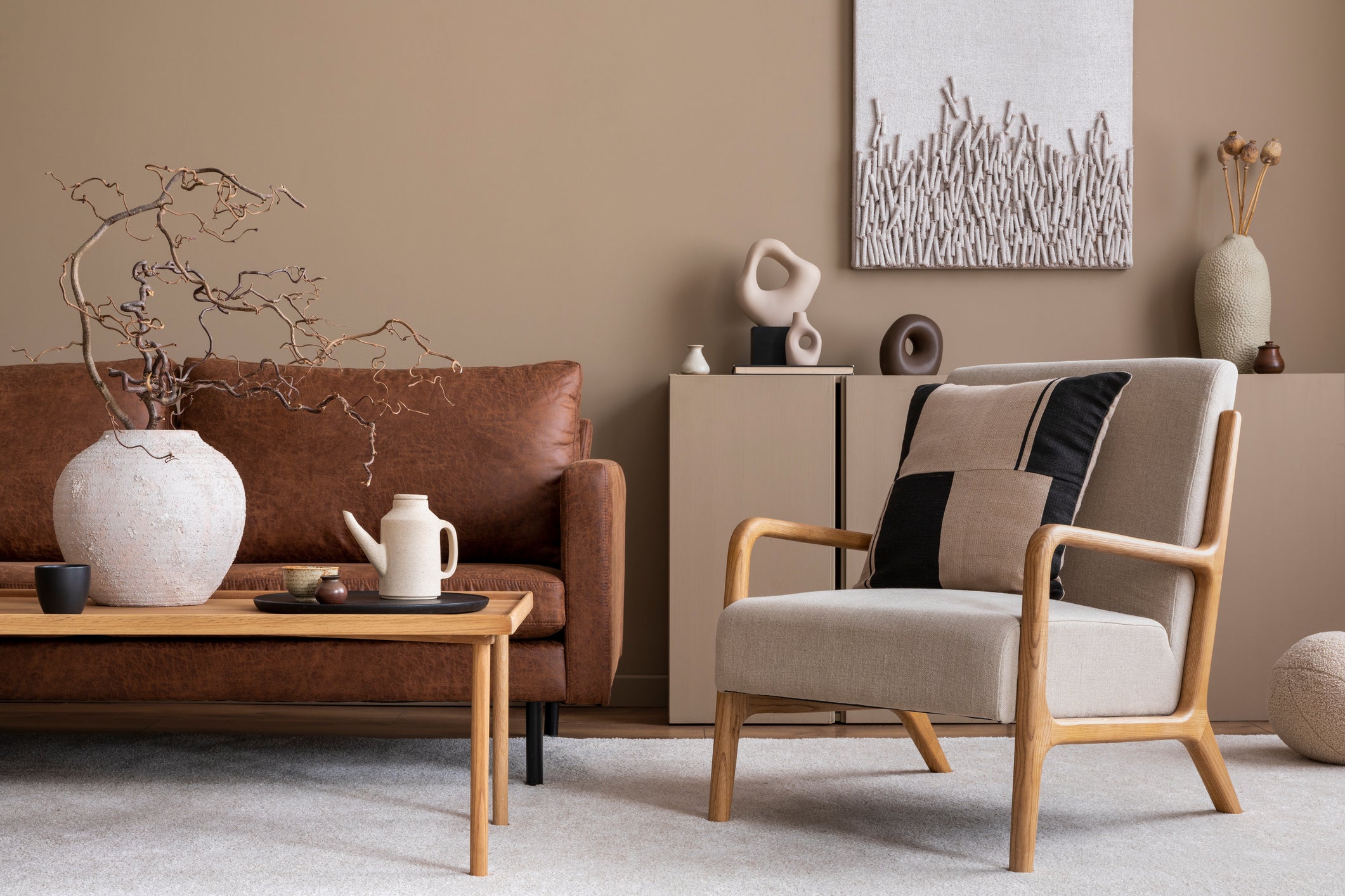 Modern living room with brown sofa, beige armchair, and decorative items.