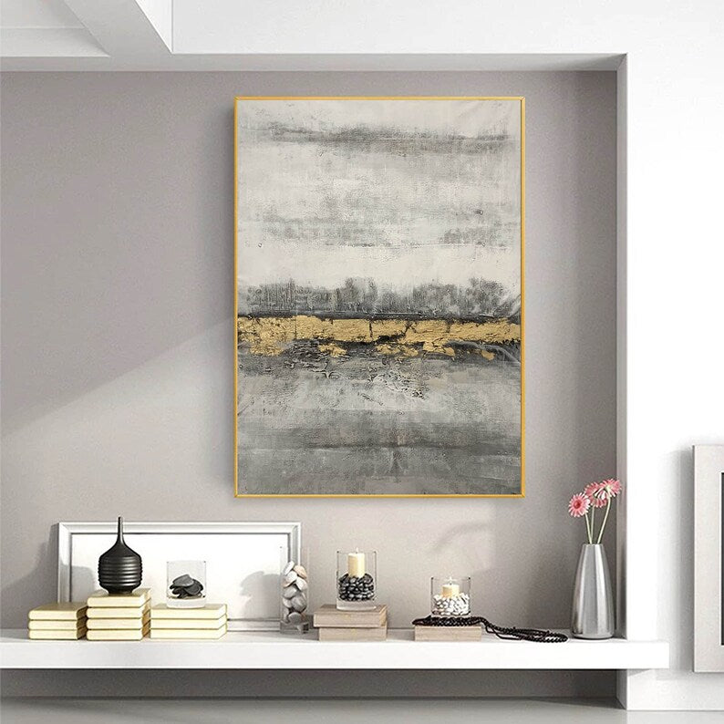 Abstract art piece with gold accents on a gray wall above a shelf with decorative items.