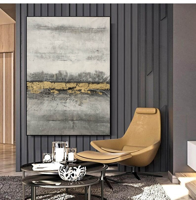 Modern interior with a beige armchair, coffee table, and abstract painting on a dark wall.