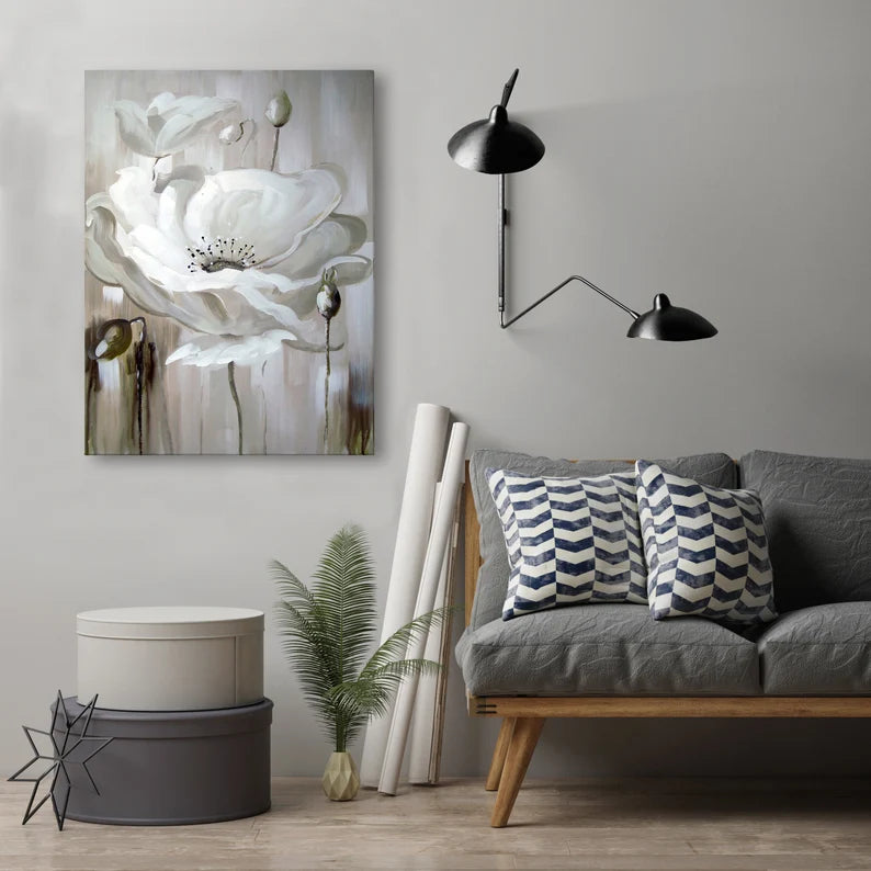 Modern living room with a gray sofa, decorative pillows, a wall lamp, and a floral painting.