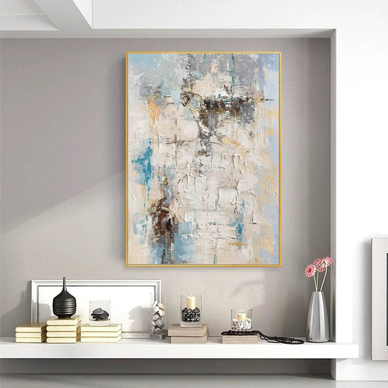 Abstract painting in a gold frame on a wall above a shelf with decorative items.