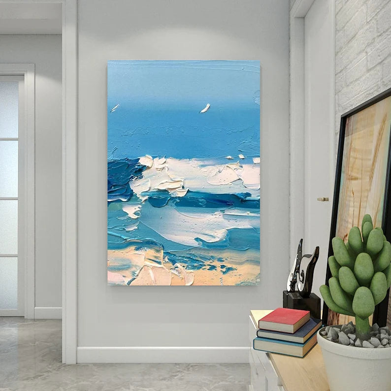 Abstract painting of a beach scene on a wall in a room with a desk and plant.