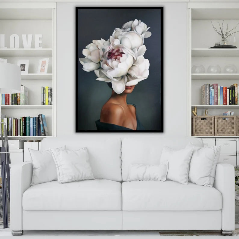 Framed artwork of a woman with flowers on her head above a white sofa in a living room.