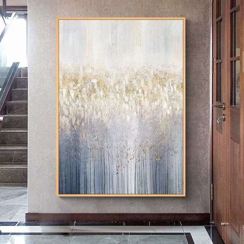 Abstract painting in a gold frame on a wall in a modern interior setting.
