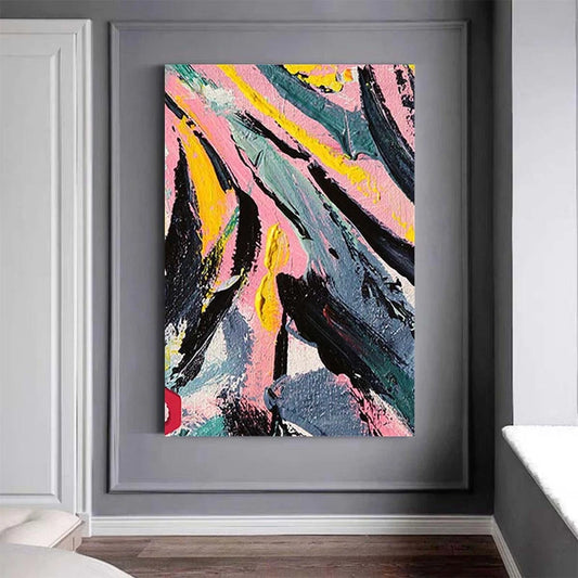 Framed abstract painting with pink, yellow, and black colors on a gray wall.