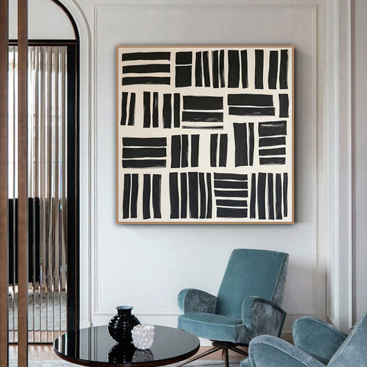 Abstract black and white artwork on a wall above a blue armchair in a stylish room.
