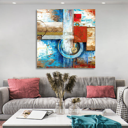 Abstract art painting on a wall above a gray sofa with decorative pillows and a coffee table.