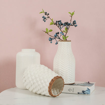 Two textured vases with wooden bases on a light surface against a pink background