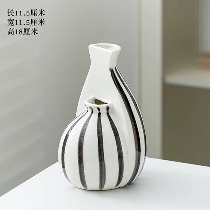 Two ceramic vases with black stripes on a white surface