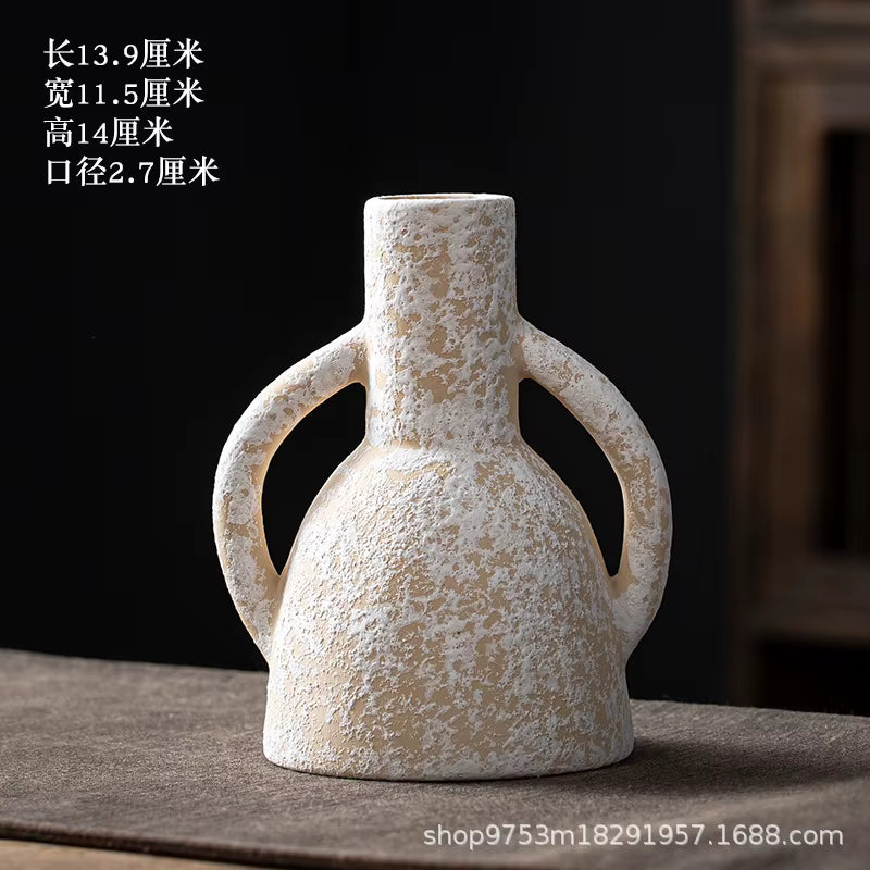 White ceramic vase with two handles on a dark surface