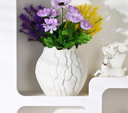 White textured vase with flowers on a white surface