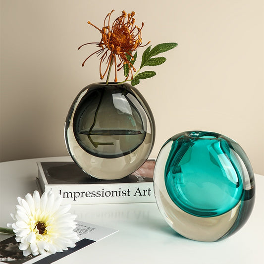 Two glass vases with flowers on a surface with 'Impressionist Art' book.