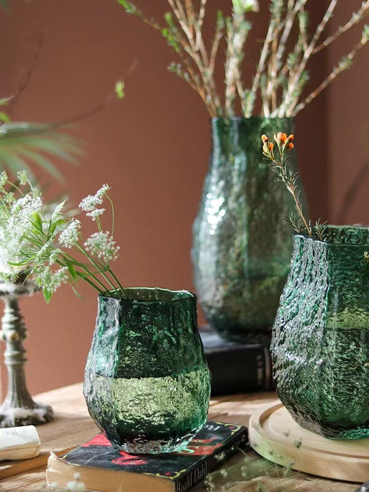 Green textured vases with plants on a wooden surface against a brown background