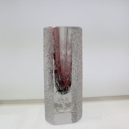 Cylindrical glass vase with textured surface and purple tint on a white background
