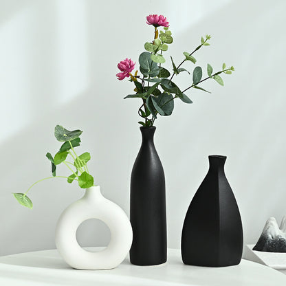 Three vases of different shapes and colors on a white surface with a light gray background