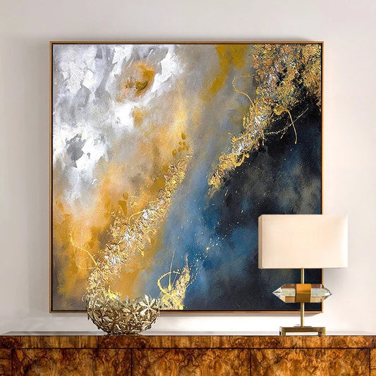 Abstract art piece with gold and blue tones on a wall above a wooden console table.
