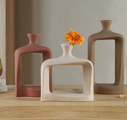 Three modern ceramic vases on a wooden surface with a neutral background