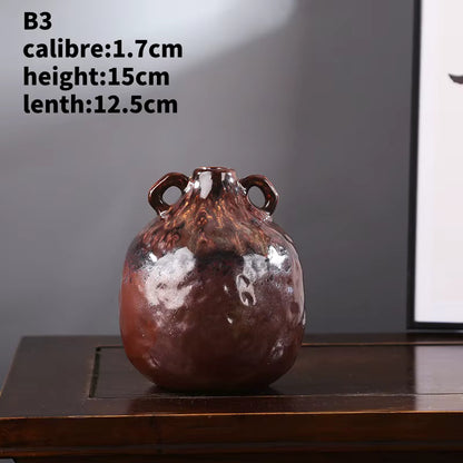 Decorative vase with handles on a wooden surface against a gray wall