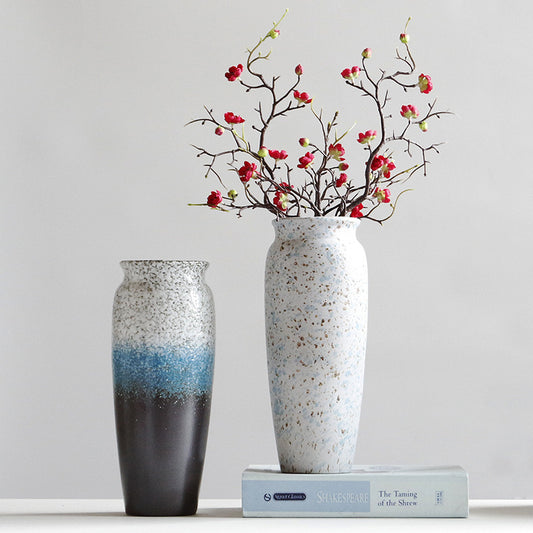 Two decorative vases with speckled patterns and a book on a light gray background