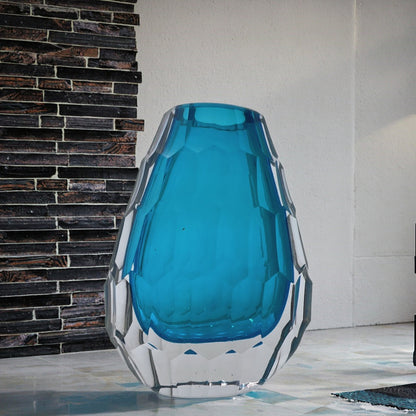 Blue glass vase with geometric design against a brick wall