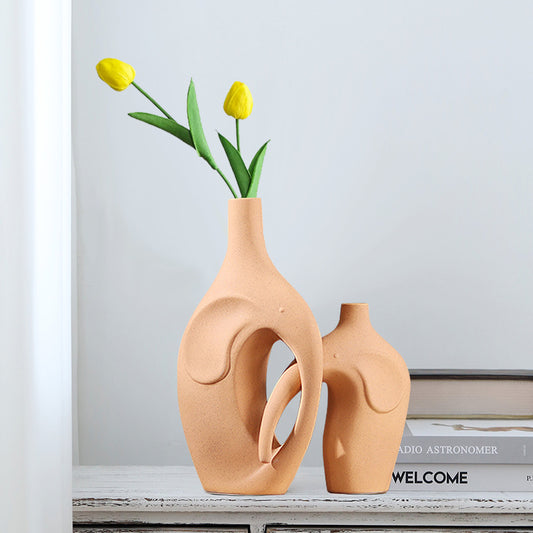 Two peach-colored vases with a unique design on a shelf.