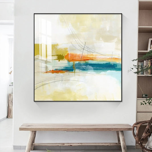 Abstract painting with orange and blue strokes on a white wall above a wooden bench.