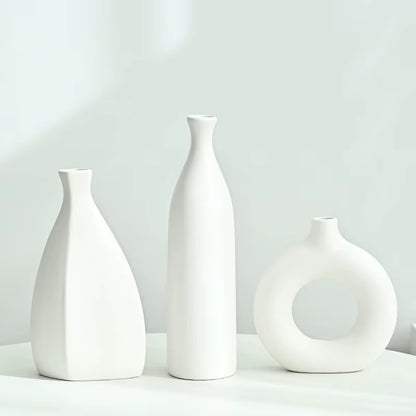 Three white ceramic vases of different shapes on a light gray background