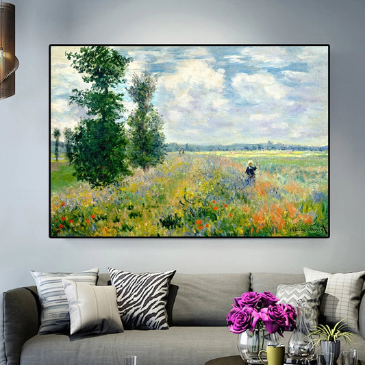Framed painting of a landscape with a field and trees on a wall above a sofa.