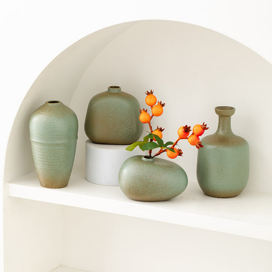 Set of green ceramic vases on a white shelf with a decorative branch.