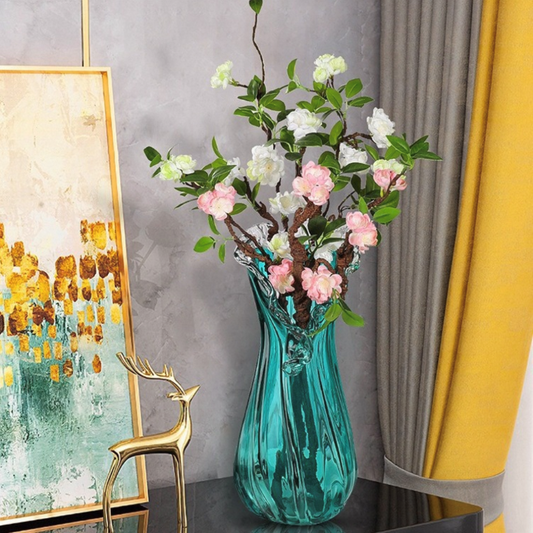 Teal vase with flowers in a room setting with a painting and decorative deer.