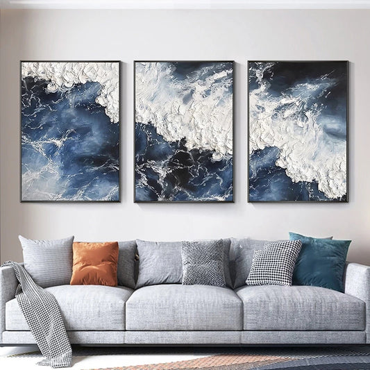 Three abstract wall art pieces above a sofa with colorful cushions.