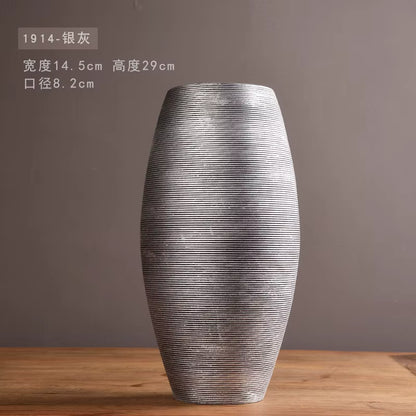 Silver textured vase on a wooden surface with a gray background