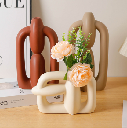 Decorative vases with a vase holding flowers on a wooden surface.