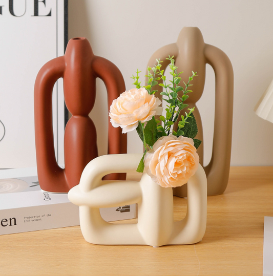 Decorative vases with a vase holding flowers on a wooden surface.
