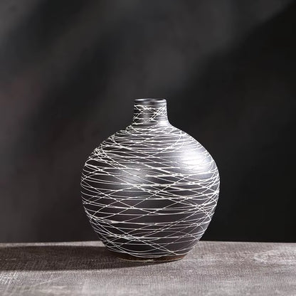 Decorative vase with white string pattern on a dark background