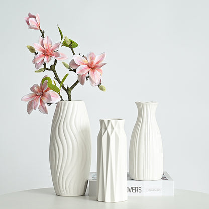 Set of three white ceramic vases with wavy design on a light gray background