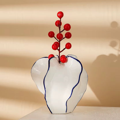White vase with blue rim holding red berries against a beige background