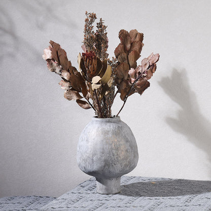 Decorative vase with dried flowers on a textured surface