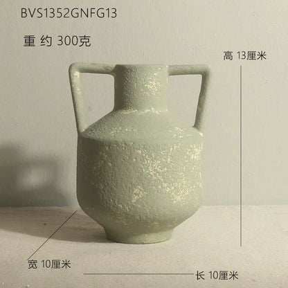 Green ceramic vase with handles on a light gray background