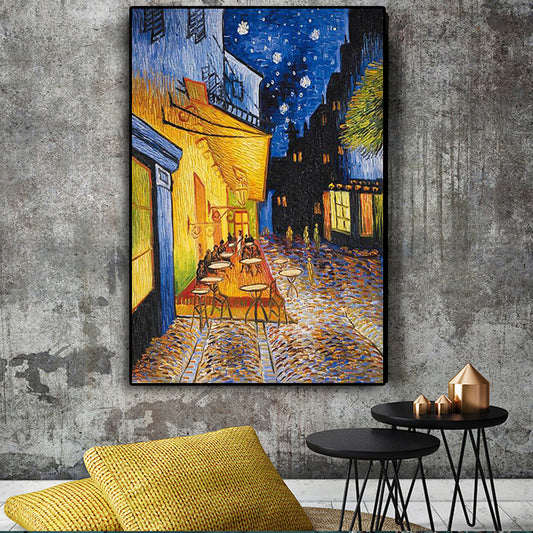 Framed artwork of a street scene with tables and chairs against a dark sky, hanging on a textured wall.