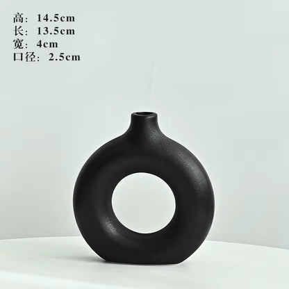 Black ceramic vase with circular design on a white background