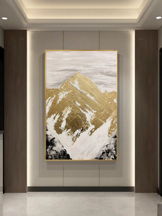 Abstract art piece with gold and white mountain design on a wall.