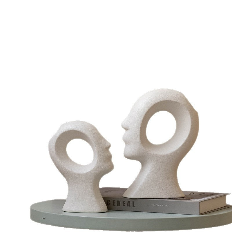 White abstract sculpture of two faces on a white background