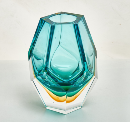Teal glass vase with geometric design on a light gray background