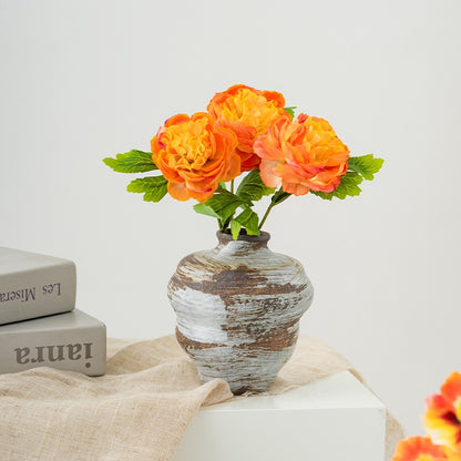 Decorative vase with orange flowers on a light surface