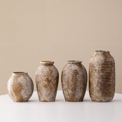 Four rustic ceramic vases of varying sizes on a light surface with a beige background