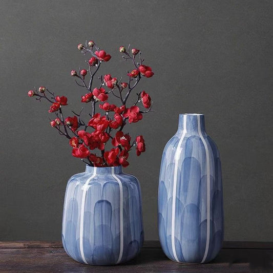 Two blue vases with floral arrangements on a dark surface against a gray background