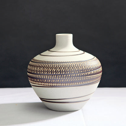 Ceramic vase with striped pattern on a white surface and black background