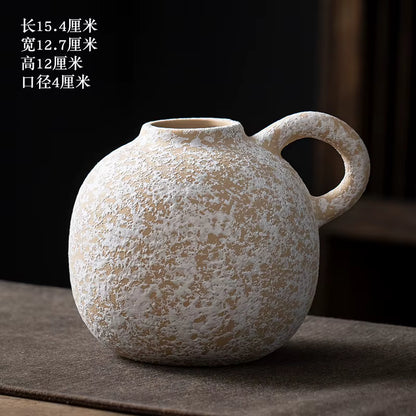 Textured ceramic vase with a handle on a dark surface