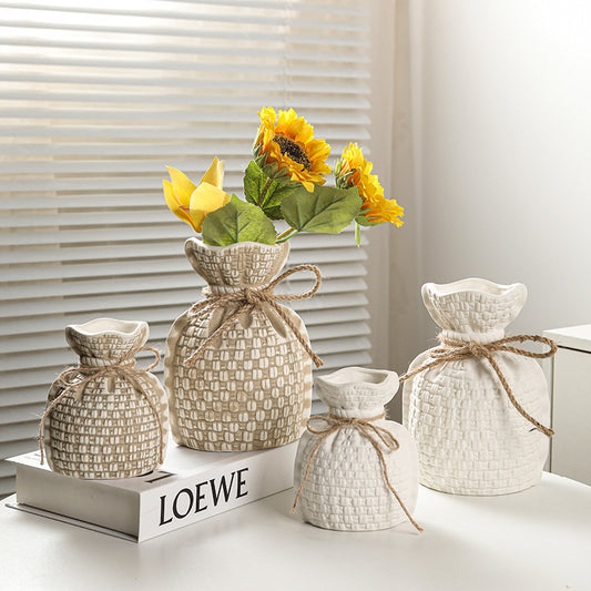 Set of decorative vases with sunflowers on a LOEWE box against a neutral background